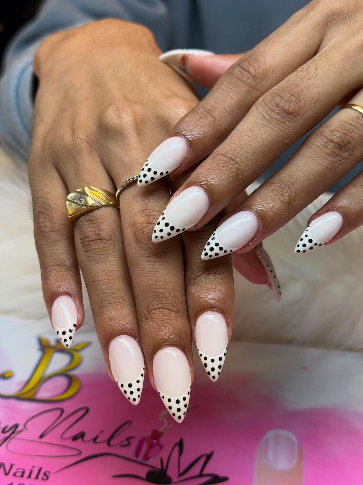 Lange almond nagels in zacht roze met zwarte stipjes op de punt