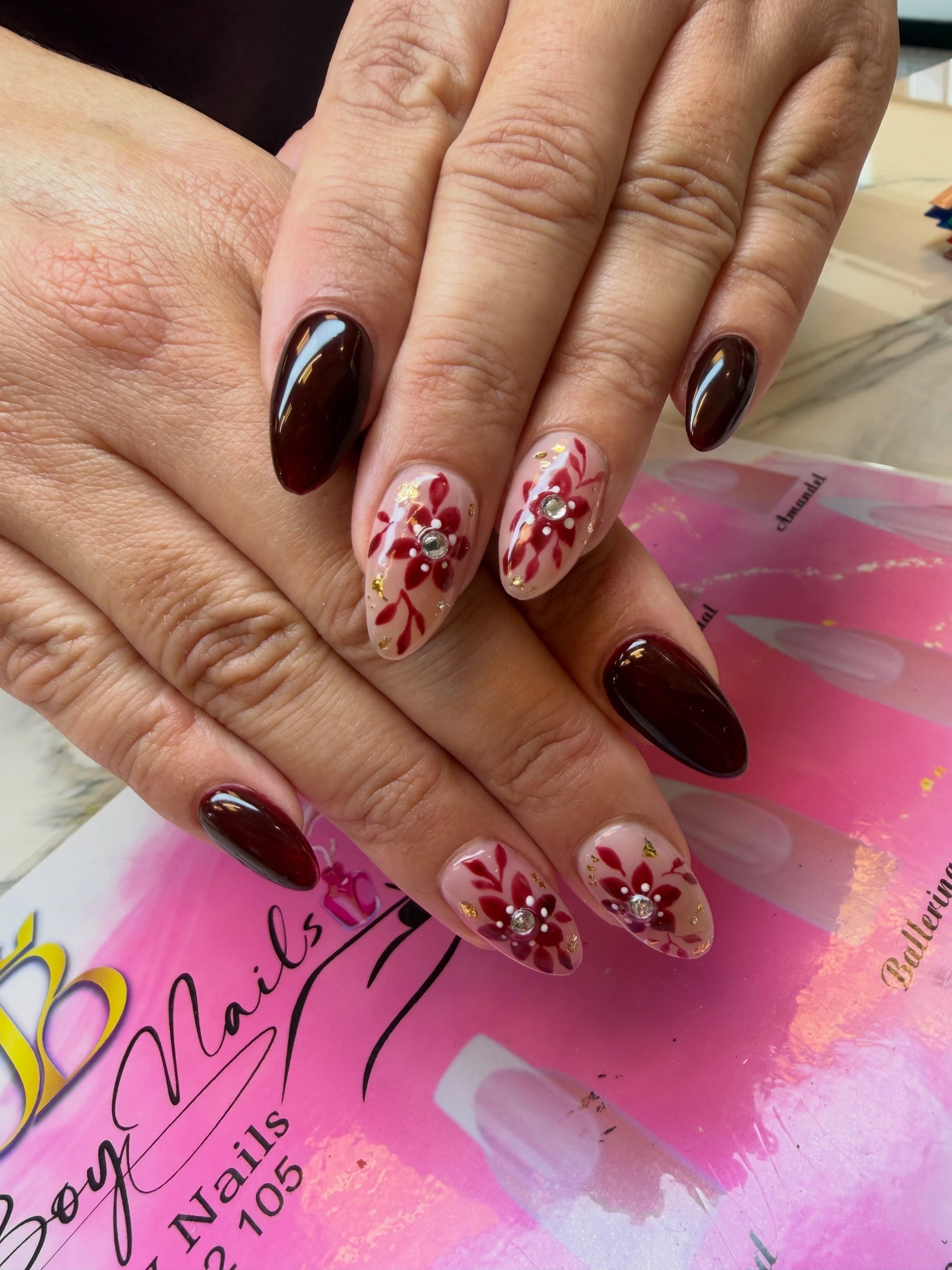 Bordeauxrode nagels met handgeschilderde bloemen en steentjes