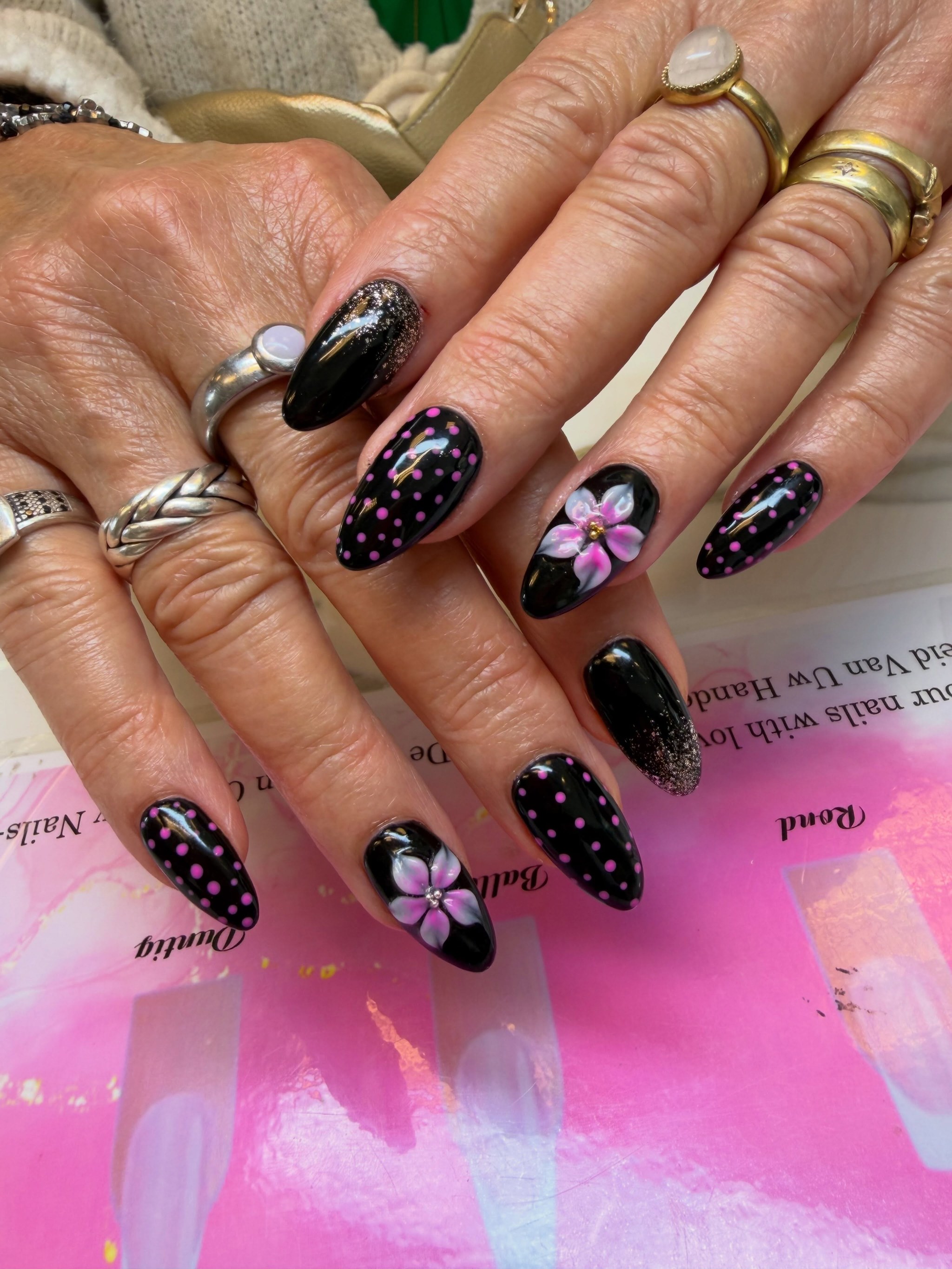Zwarte nagels met roze stippen en een geschilderde bloem